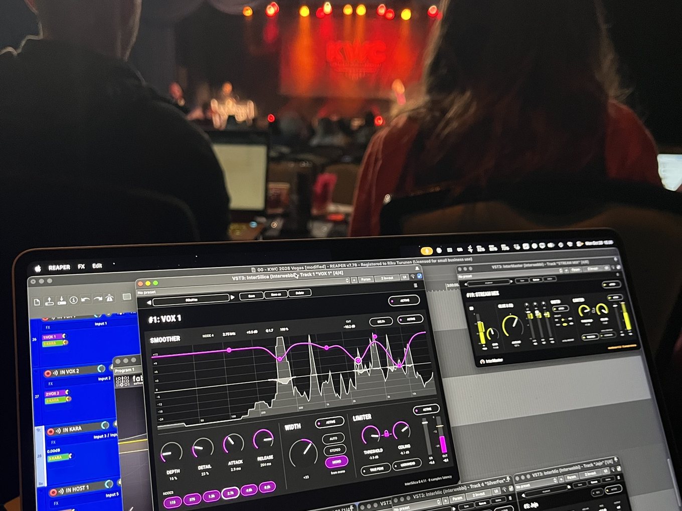 A laptop running InterSilica, InterMaster and InterMic in REAPER during a show, with the KWC stage lit red beyond it